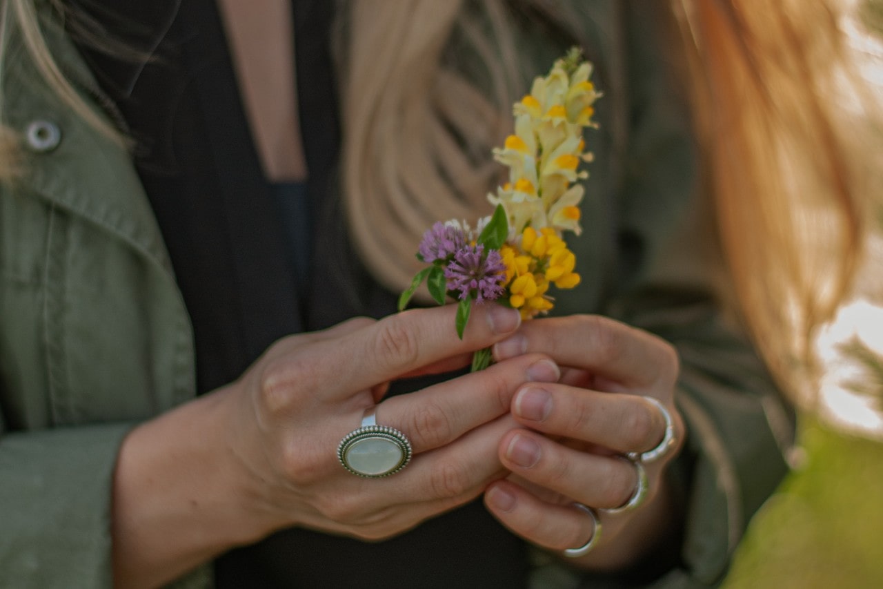 Stylish woman with fashion ring stack holding colorful flowers