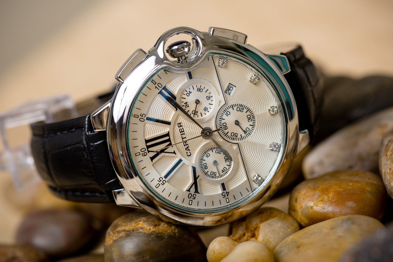 A Cartier timepiece sits on a group of pebbles on the shore of a beach to prevent it from water damage