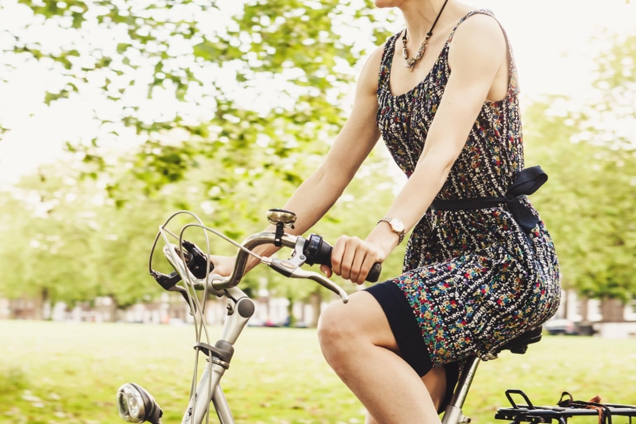 A woman wearing a watch rides her bike on a sunny day