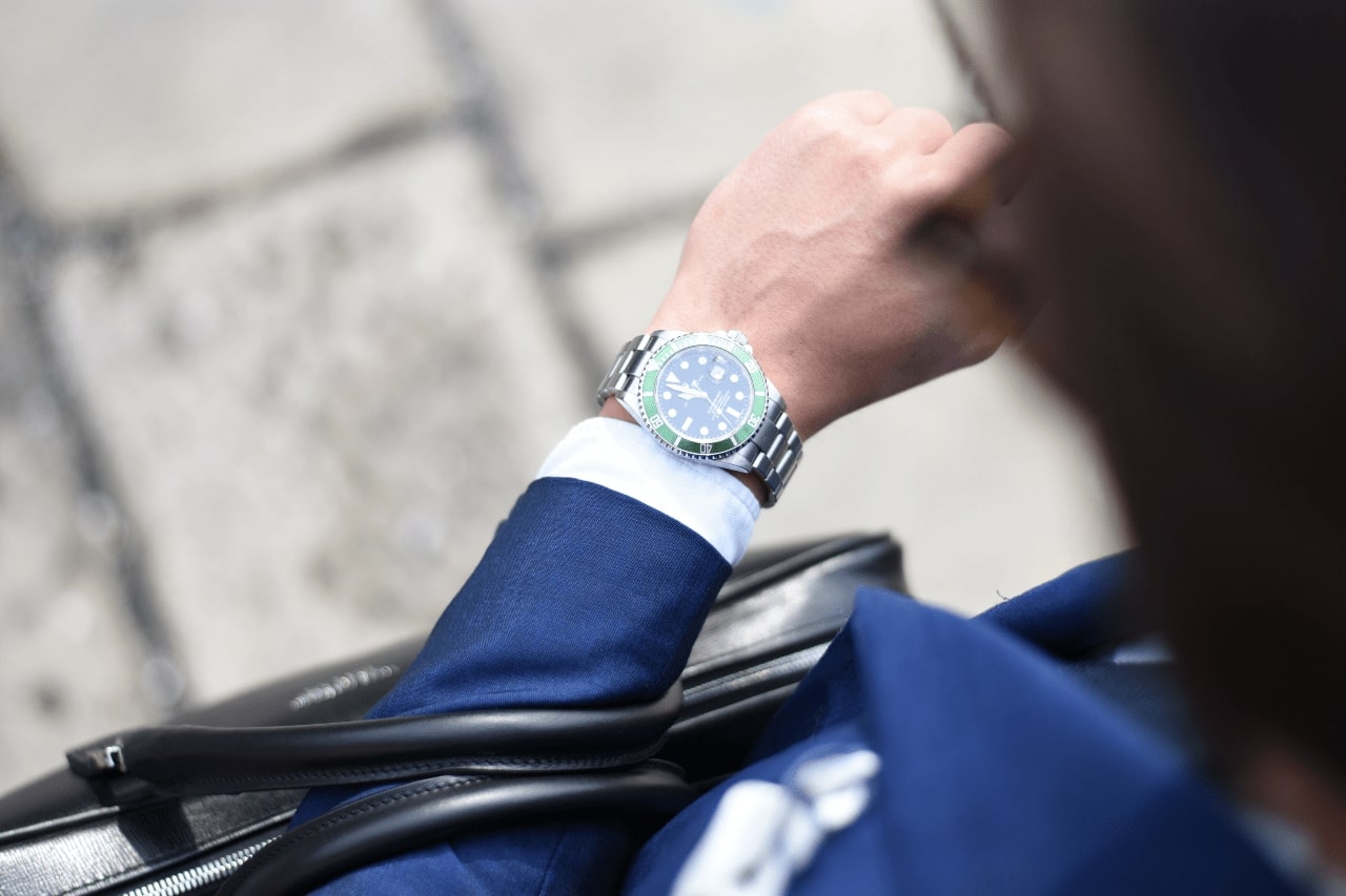  A man wearing a suit looks down at his Rolex watch
