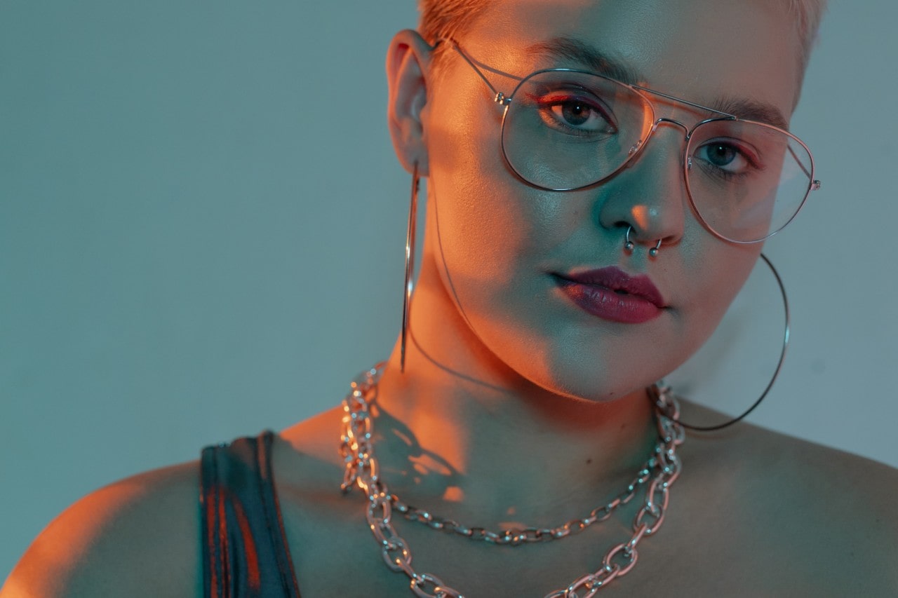 Woman wearing two chunky chain necklaces and large hoop earrings