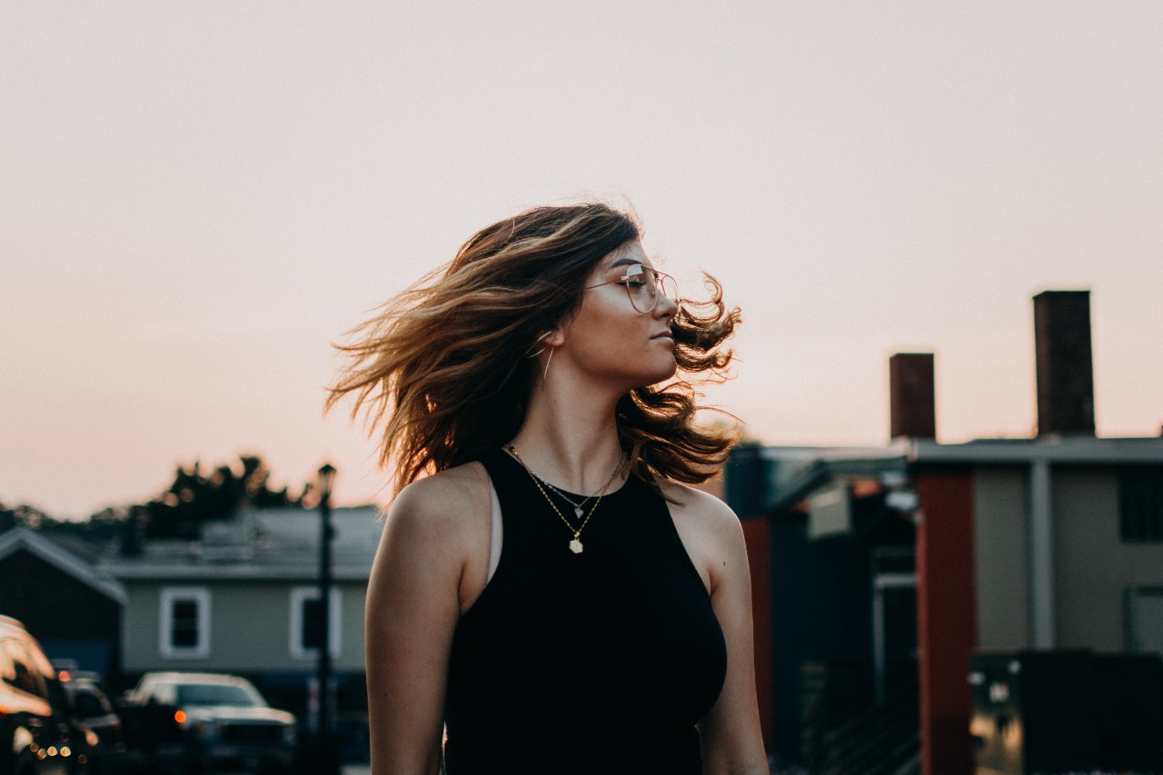 At sunset, a woman wearing necklaces shakes her hair