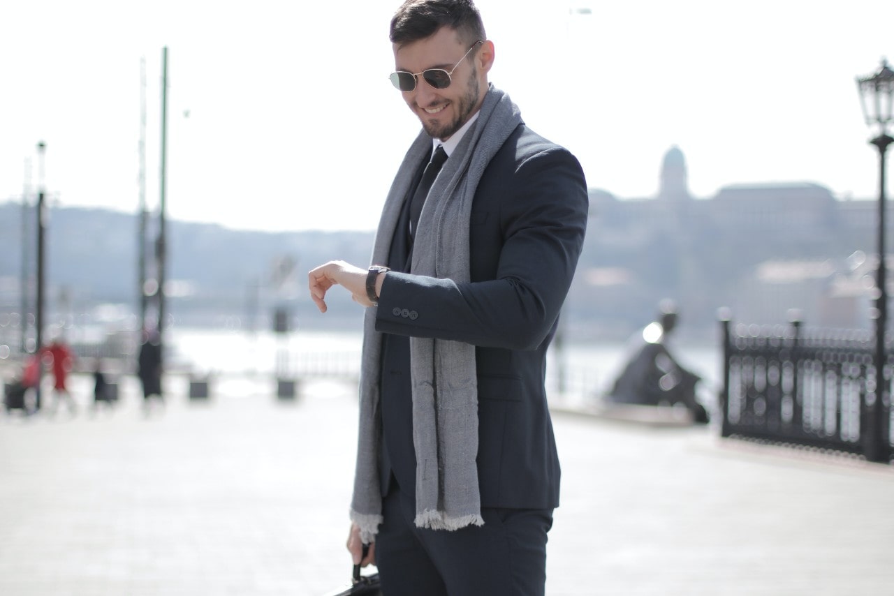 a man standing near the water looking at his watch