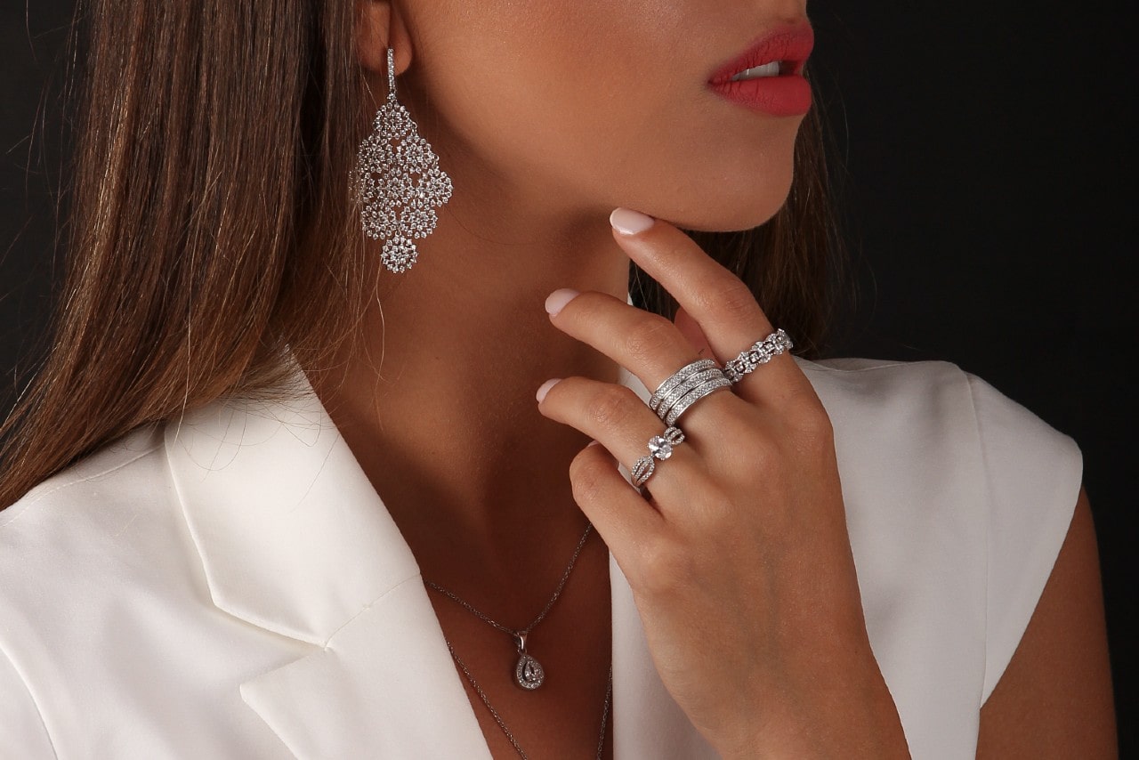 a woman wearing diamond jewelry and a white short-sleeved blazer.