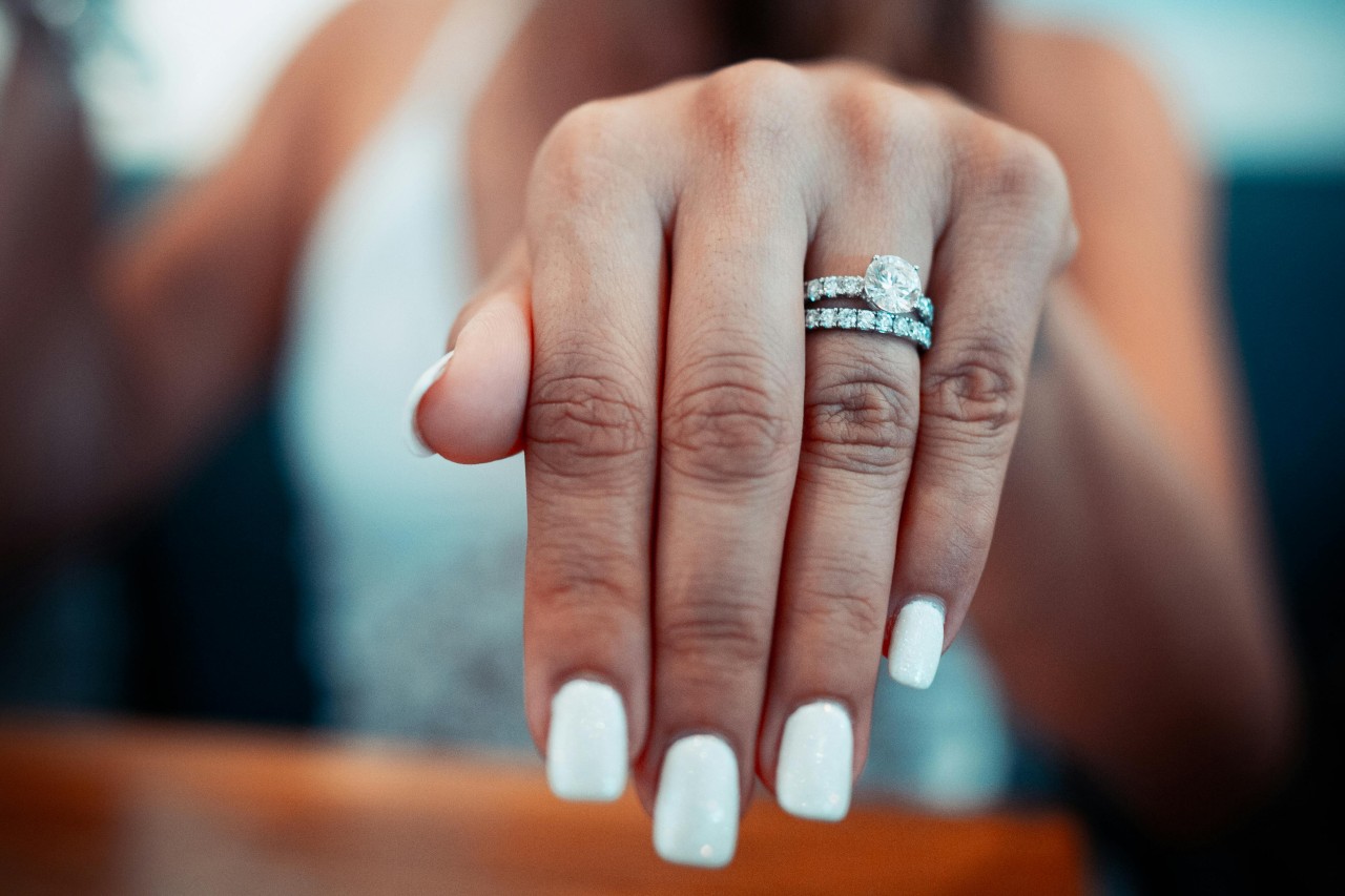 A woman shows off her side stone engagement ring.