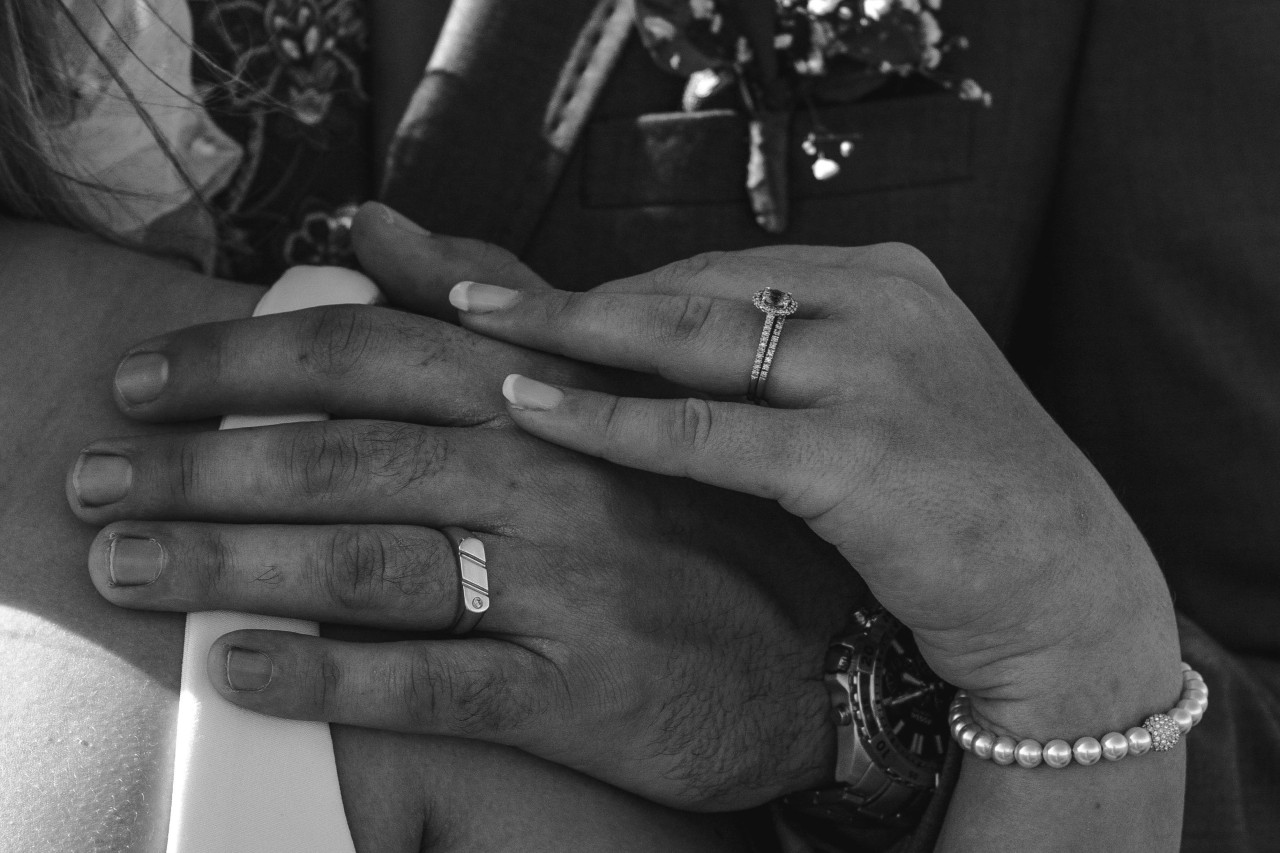 A black and white photo of a bride’s and groom’s hands.