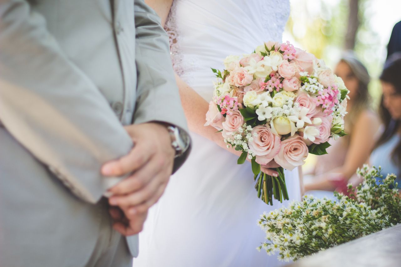 A close-up of a bride and groom standing at the altar, the bride holding a colorful bouquet.