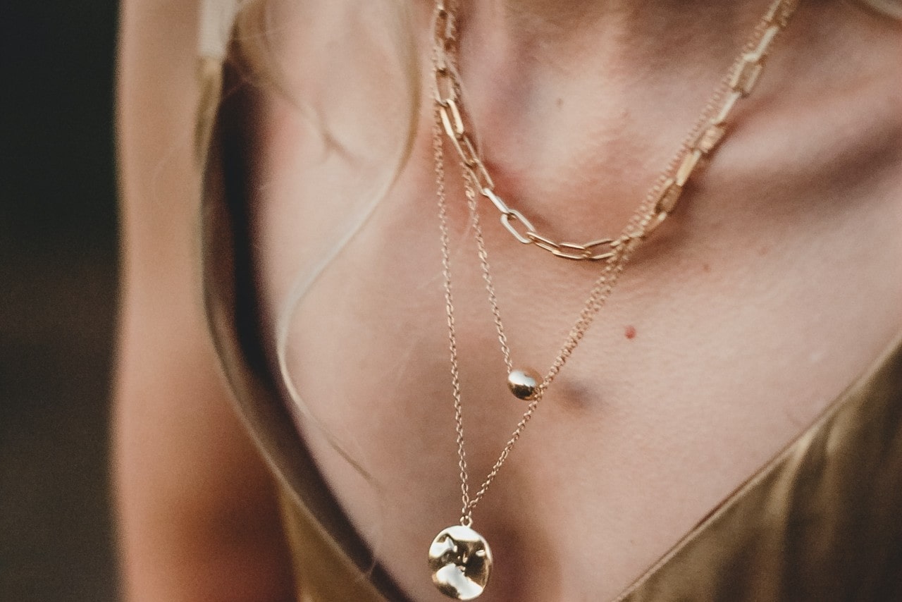 close-up image of a woman wearing three gold chain necklaces