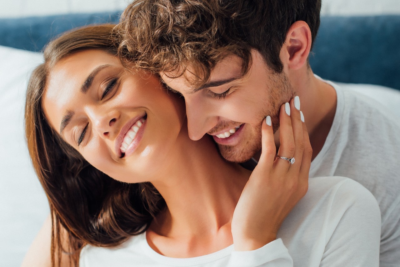 a lady wearing an engagement ring embracing a man