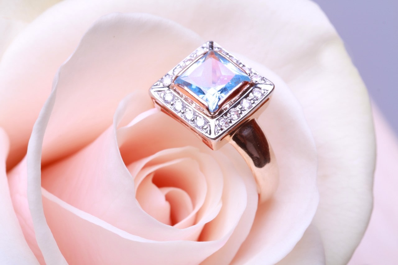 a diamond engagement ring nestled in a pink rose