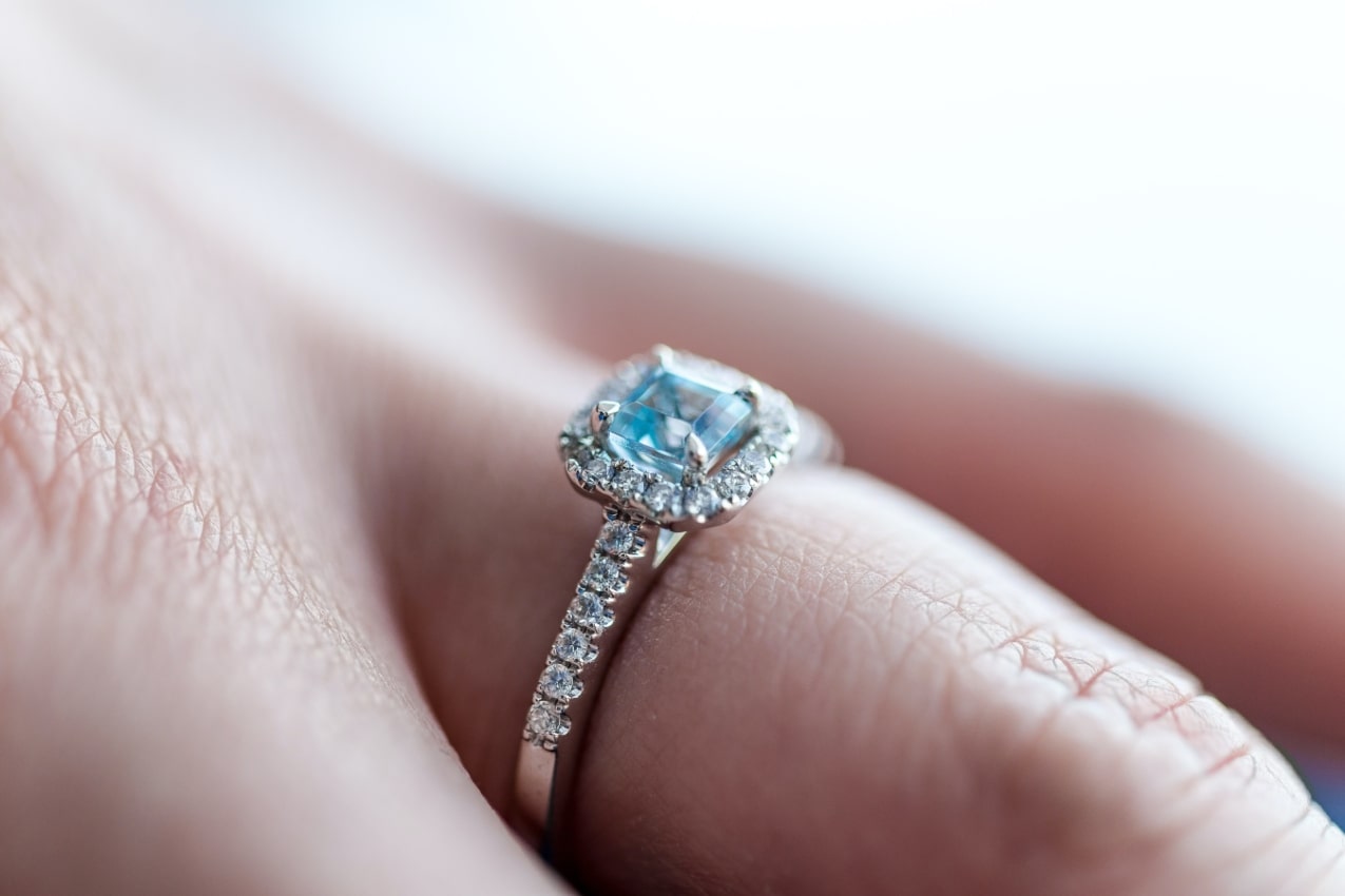 a close-up of a woman’s hand, a unique engagement ring adorning her finger